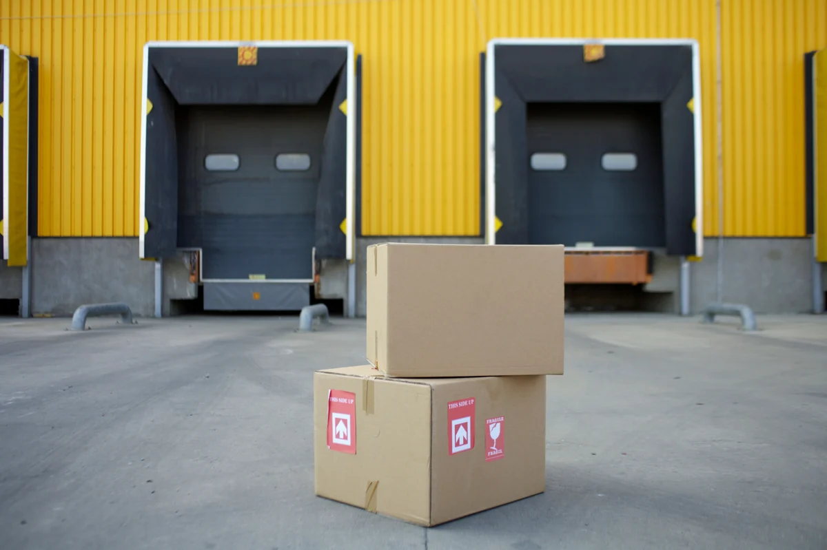 Two cartons near yellow warehouse loading gates