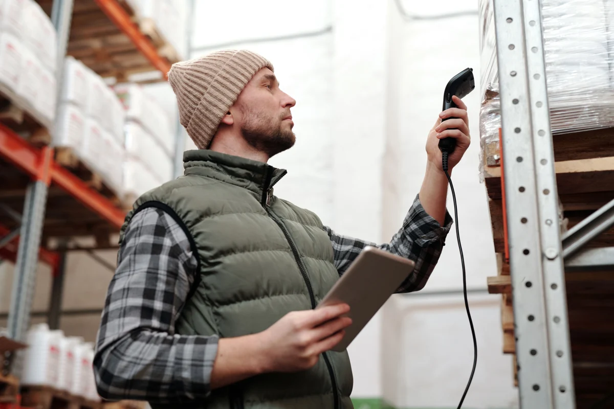 Warehouse worker scanning shrink-wrapped goods on a pallet